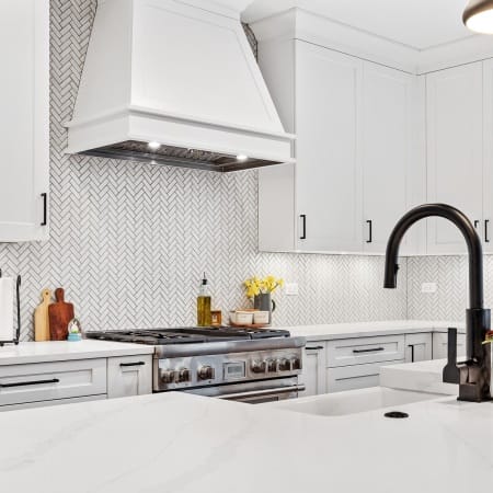 Cabinetry Style Hood on White Herringbone Backsplash