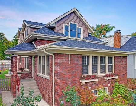 Traditional Red Brick Bungalow with Sloping Second Story and Dormers