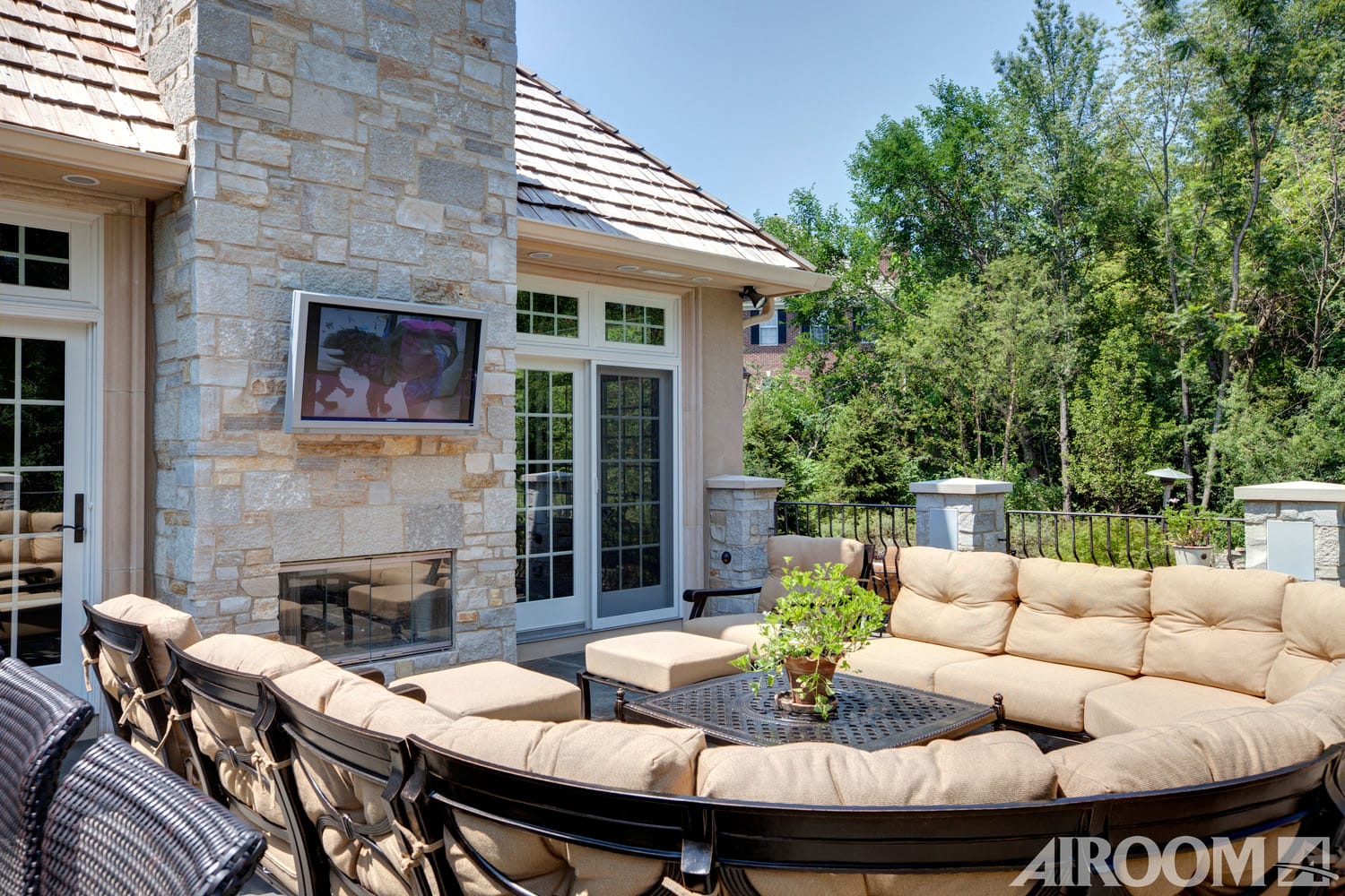 Image of an exterior patio lounge area with a mounted TV by Airoom®