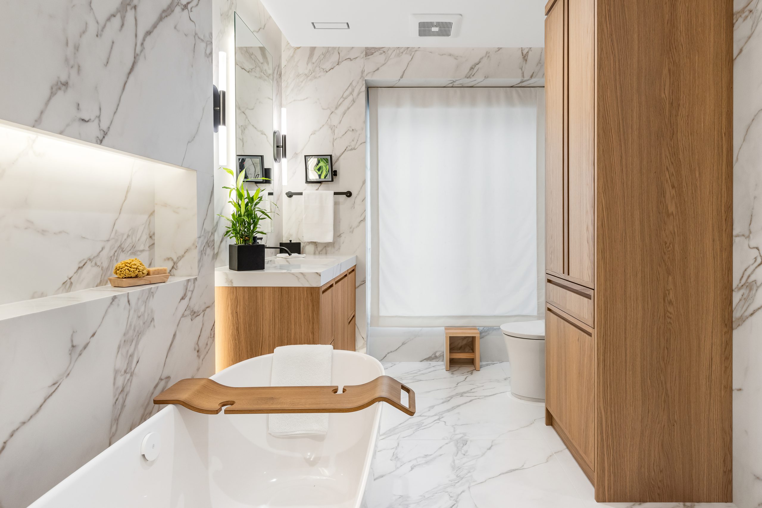All white bathroom with warm-toned cabinets.