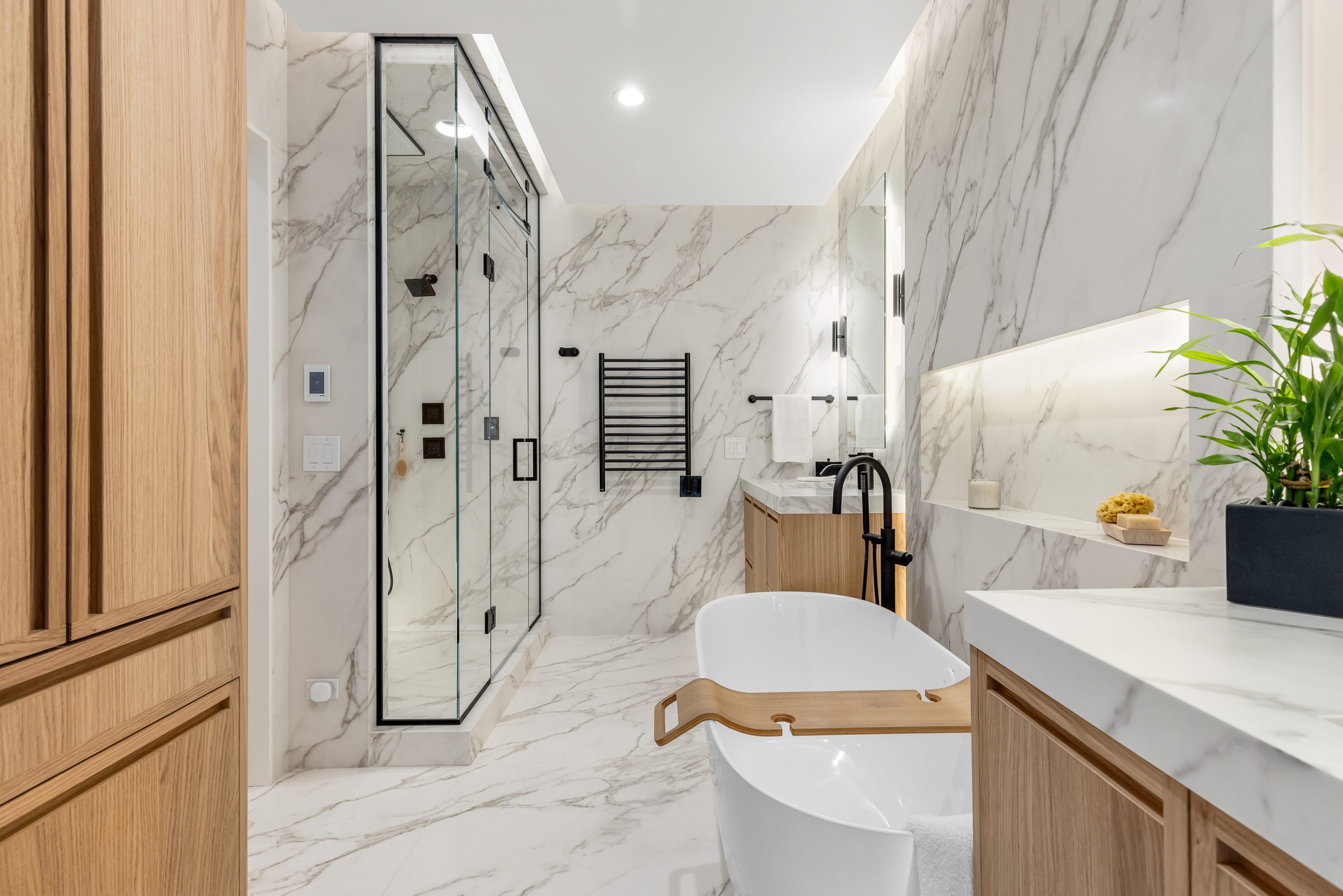 White, marble bathroom in Hinsdale, IL with a large soaking tub, dual vanities, and a large shower.